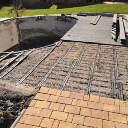 a pool under construction with a brick walkway and grass