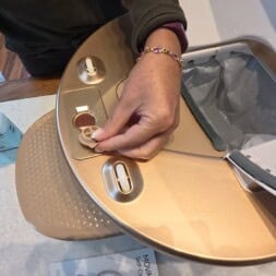 Automatic litter box test: Self-cleaning litter box without odor - Mova LR10 30 A person’s hand placing a cleaning pad onto a gold-colored robotic mop with its lid open, similar in convenience to an automatic litter box. A bottle of cleaning solution and an instruction manual are on the table nearby. www.commaik.de