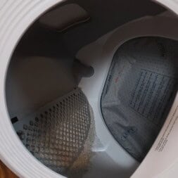 Automatic litter box test: Self-cleaning litter box without odor - Mova LR10 39 Close-up view of the inside of a clothes dryer, showing the drum, lint filter, and a drying pad labeled LEFT and RIGHT. The clean interior is well-lit—distinct from a litter box in its tidy appearance and function. www.commaik.de