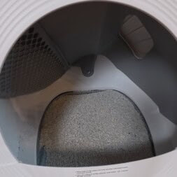 Automatic litter box test: Self-cleaning litter box without odor - Mova LR10 40 The image shows the inside of an automatic self-cleaning litter box, partially filled with clean cat litter, viewed from above with the litter box lid open. www.commaik.de