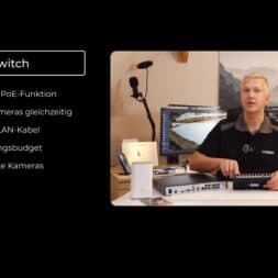 Install surveillance cameras yourself - IP camera network explained simply 38 A man sits at a desk with various network devices, including a PoE switch, and explains its functions for IP camera setups. The text on the left lists the advantages of the PoE switch in German. Several monitors and a microphone can be seen in the background. www.commaik.de