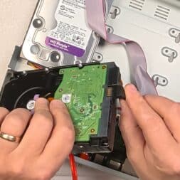 Expand Reolink NVR storage space - Installing and configuring hard disks correctly 24 A person's hands connect a data cable to a green circuit board on a hard disk, while an open computer case, another installed hard disk and a Reolink NVR can be seen in the background. www.commaik.de