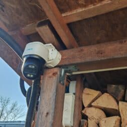 The best Reolink 4k PTZ surveillance cameras in comparison: 823S2 vs 823S1 vs TrackMix vs TrackFlex in test 20 A Reolink 4K PTZ security camera is attached to a wooden beam under a roof near a pile of firewood. The camera is connected with black cables, and in the background the sky is clear and sunny. www.commaik.de