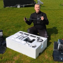 Lymow One Plus in test: RTK robot mower for large areas & difficult terrain 10 A man kneels in the grass next to a large polystyrene box containing various parts and holds one of them up. On either side of him are two large black Lymow One Plus robots ready for assembly. www.commaik.de