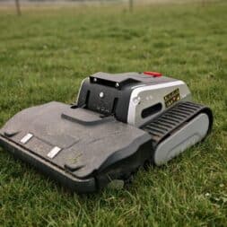 Lymow One Plus in test: RTK robot mower for large areas & difficult terrain 6 A Lymow One Plus robotic lawnmower with tank-like treads is standing on a lawn and appears to be slightly dirty from use. The device is mostly black and gray with some yellow stickers and a visible red button on top. www.commaik.de