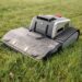 Lymow One Plus im Test: RTK Mähroboter für große Flächen & schwieriges Gelände 62 Ein Lymow One Plus Rasenmähroboter mit panzerähnlichen Raupen sitzt auf grünem Gras, leicht verschmutzt vom Gebrauch, in einem Außenbereich. www.commaik.de