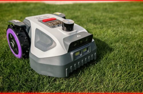 Robot mower without boundary wire in test: Anthbot M5 LiDAR for small gardens An Anthbot M5 robotic lawnmower without a boundary wire with a screen and a large central button sits on green grass, ready to mow. The image is equipped with LiDAR technology and is framed by a bright red border. www.commaik.de