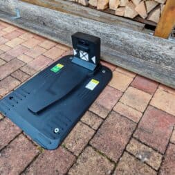 Robot lawn mower without boundary wire in test: LiDAR vs RTK in comparison (ANTHBOT M5 vs M9) 16 A black Anthbot robotic lawnmower charging station stands on a brick patio near a pile of wood and a lawn. www.commaik.de