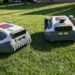 Mähroboter ohne Begrenzungskabel im Test: LiDAR vs RTK im Vergleich (ANTHBOT M5 vs M9) 66 Zwei Anthbot Mähroboter stehen Seite an Seite auf grünem Gras, das Sonnenlicht beleuchtet ihre Räder und Sensoren in einem Hinterhof oder Garten. www.commaik.de