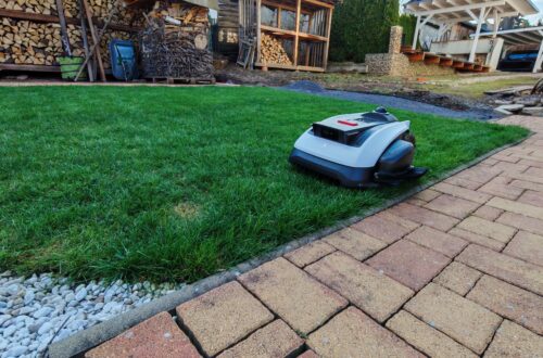 ECOVACS GOAT O1200 LiDAR Pro Review: A Cordless Robotic Lawn Mower with LiDAR & Trimmer A robotic lawn mower is in operation on a green lawn near a stone path; in the background, stacked firewood and wooden structures can be seen. This robotic lawn mower uses advanced LiDAR technology for precise navigation, so no boundary wire is required. www.commaik.de