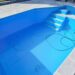 Hoher Chlorverbrauch im Pool: Warum 20 Liter Chlor in zwei Wochen verschwanden 25 Ein fast leerer Swimmingpool mit etwas Schmutz am Boden, einem grünen Schlauch und einer kleinen Pumpe. Eine Treppe führt in den Pool hinab, der von hellen Fliesen umgeben ist – Umstände, die den Chlorverbrauch beeinflussen können, wenn Sie den Pool für den Gebrauch vorbereiten. www.commaik.de