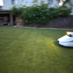 TerraMow V1000, V600, and Mini 500 Review: Robotic Lawn Mowers Without RTK and Lidar? 10 A Terramow V600 robotic lawn mower equipped with headlights is mowing a lawn near a house and garden wall in the evening or early morning. www.commaik.de