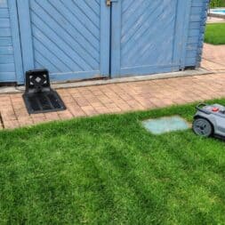 TerraMow V1000, V600, and Mini 500 Review: Robotic Lawn Mowers Without RTK and Lidar? 32 A Terramow V600 robotic lawn mower is mowing a lawn near a paved path that leads to a blue wooden shed. Next to the shed are a black plastic object and a pile of bricks. A swimming pool can be seen in the background. www.commaik.de