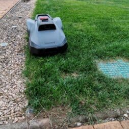 TerraMow V1000, V600, and Mini 500 Review: Robotic Lawn Mowers Without RTK and Lidar? 33 A robotic lawn mower like the Terramow V600 drives from a gravel path onto a lawn in the backyard, which is surrounded by lush greenery and a stone border. www.commaik.de
