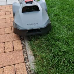 TerraMow V1000, V600, and Mini 500 Review: Robotic Lawn Mowers Without RTK and Lidar? 37 A gray robotic lawn mower called the "Terramow V1000" is mowing the edge of a green lawn next to a path made of bricks and stones, demonstrating the efficiency of this state-of-the-art robotic lawn mower. www.commaik.de