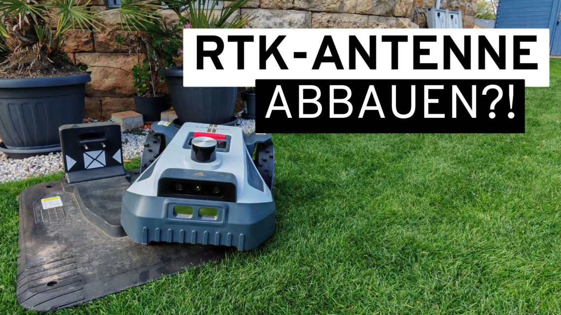 Garden 1 A robotic lawn mower at its charging station on a green lawn with the text "REMOVE RTK ANTENNA?!" superimposed, while users prepare to store the robotic lawn mower for the winter. www.commaik.de