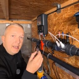 Pool winterfest machen: Wasser ablassen, Technik einlagern und das Becken abdecken 8 Ein Mann hält während des Winterfestes einen Wassersensor vor eine an einer Holzwand befestigte Poolfilteranlage. www.commaik.de