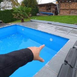 Pool winterfest machen: Wasser ablassen, Technik einlagern und das Becken abdecken 40 Eine Hand, die während des Winterfestes auf eine Einlaufdüse in einem strahlend blauen Schwimmbecken zeigt. www.commaik.de